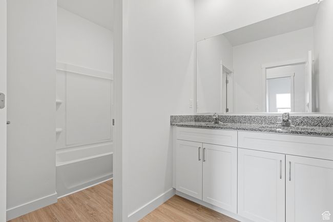 Full bath featuring double vanity, wood finished floors, baseboards, and a sink | Image 7