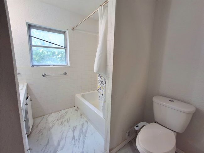 Full bathroom featuring vanity, toilet, shower / tub combo with curtain, and marble look tile flooring | Image 22