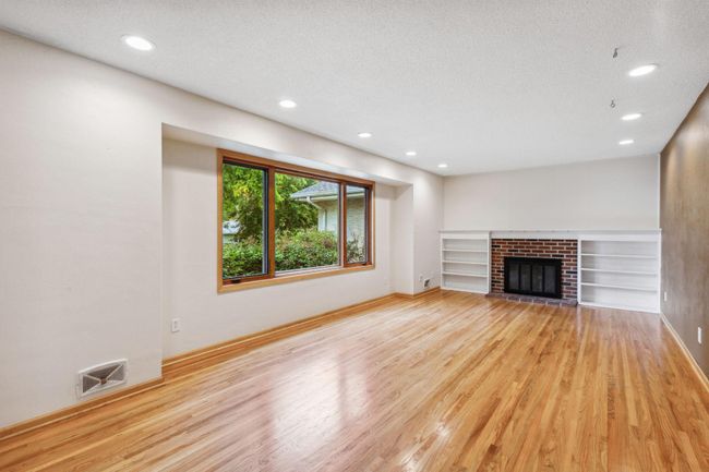 Living room has wood floors and wood burning fireplace. | Image 9