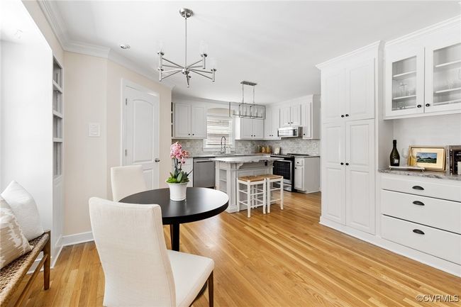 View of spacious eat-in area off of the kitchen. The eat-in offers hardwood floors, 2nd pantry and bar area with glass doors and three drawers. Not visible in this picture are cabinets/shelving, large window and door to deck. | Image 19