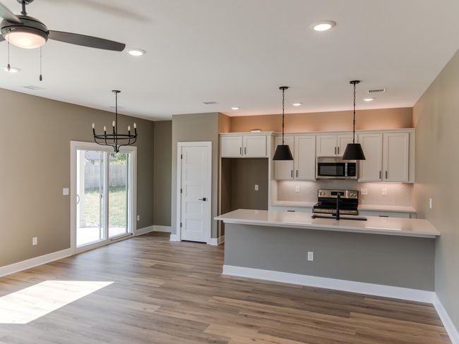 Kitchen featuring light hardwood / wood-style floors, appliances with stainless steel finishes, white cabinetry, and decorative backsplash | Image 4