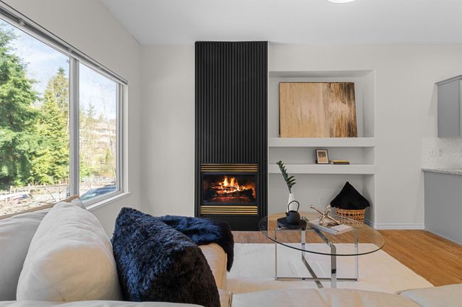 Living room with wood finished floors, a glass covered fireplace, and built in features | Image 9