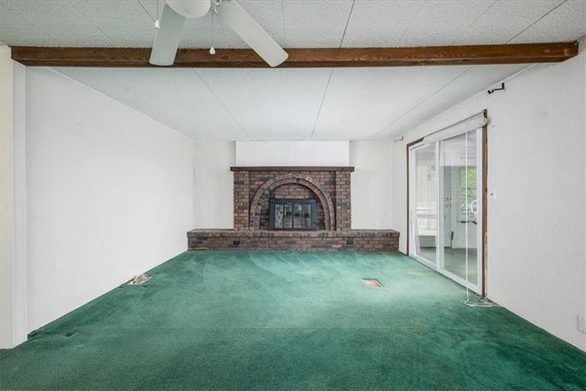 Unfurnished living room with ceiling fan, a fireplace, beam ceiling, and carpet | Image 13