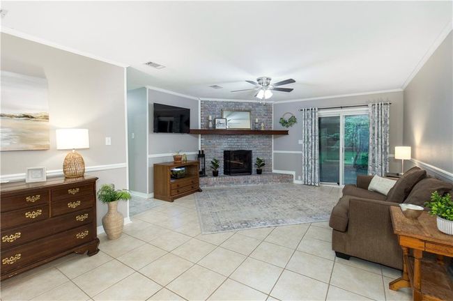 Living area featuring ornamental molding, a ceiling fan, light tile and a brick fireplace | Image 4