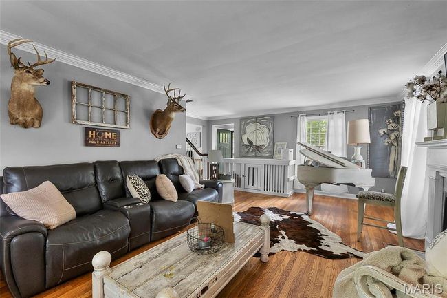 Living room featuring stairway, crown molding, wood finished floors, and a fireplace | Image 5