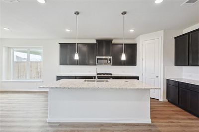 Kitchen featuring light stone counters, sink, wood-type flooring, and a kitchen island with sink | Image 2