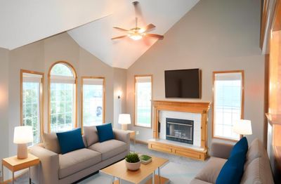 Carpeted living room with a fireplace, ceiling fan, and high vaulted ceiling | Image 2