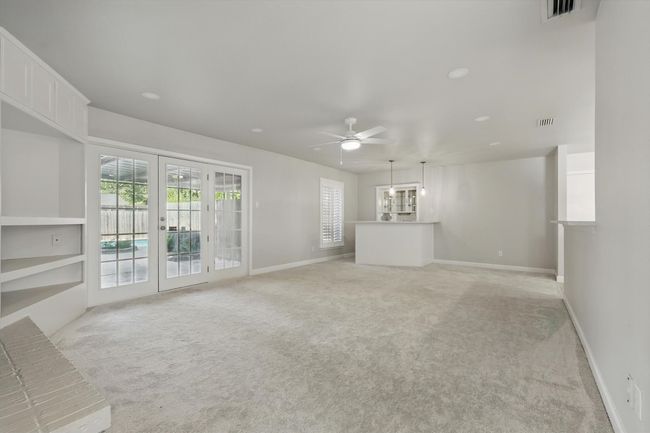 Unfurnished living room with baseboards, a ceiling fan, visible vents, and light colored carpet | Image 13