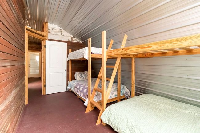 Bunkhouse bedroom with wooden and metal walls, finished concrete flooring, and vaulted ceiling | Image 26