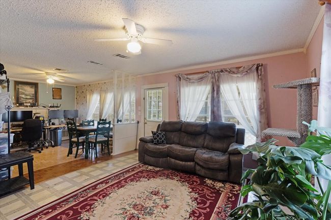 Living room with crown molding, ceiling fan, and a textured ceiling | Image 11