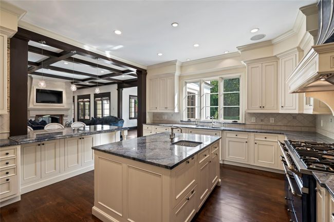 Kitchen featuring a center island with sink, sink, beamed ceiling, and cream cabinetry | Image 5