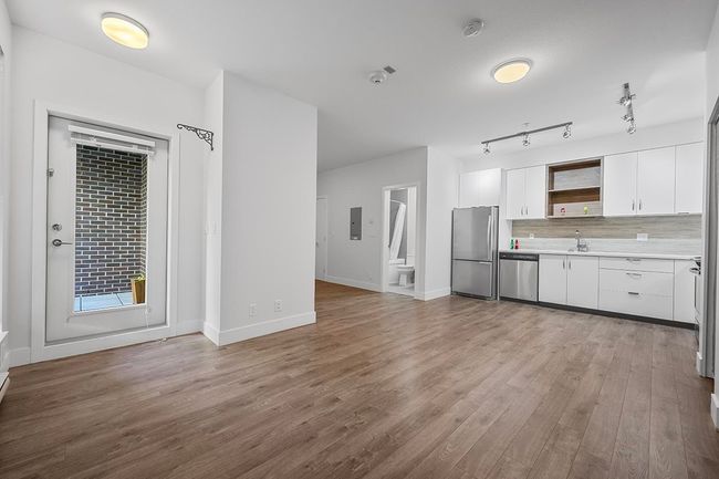 Kitchen featuring stainless steel appliances, light countertops, open shelves, wood finished floors, and white cabinetry | Image 9