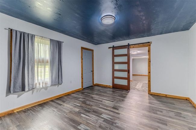 Spare room with a barn door, baseboards, and wood finished floors | Image 28