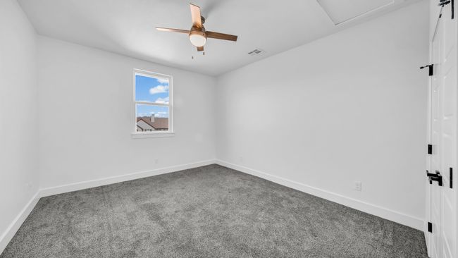 Empty room featuring a ceiling fan, baseboards, visible vents, carpet floors, and attic access | Image 33