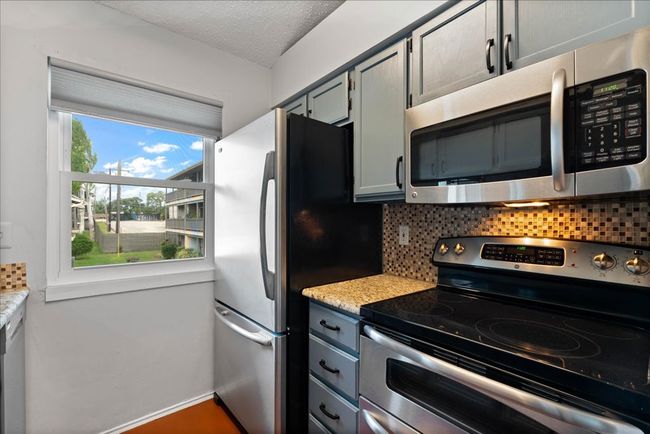 Kitchen featuring stainless steel appliances, decorative backsplash, light countertops, baseboards, and a textured ceiling | Image 5