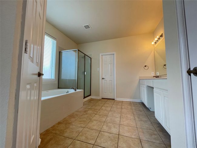 Bathroom with a stall shower, vanity, a garden tub, and tile patterned flooring | Image 5