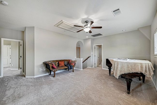 Family room with attic access, a ceiling fan, carpet flooring, and arched entryway | Image 23