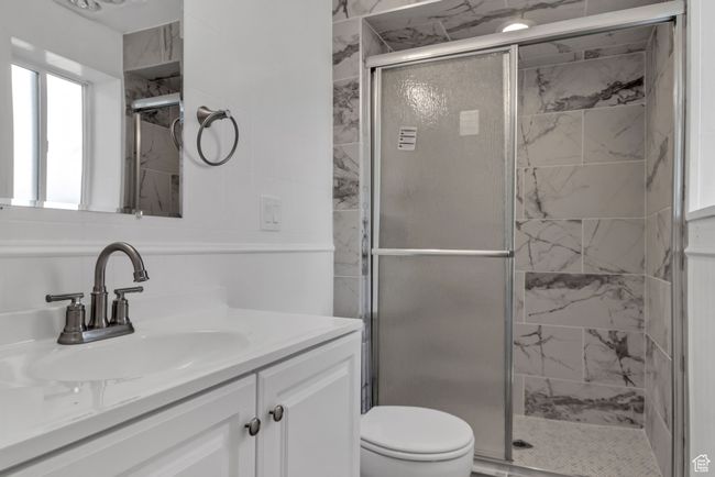 Full bathroom featuring a stall shower, toilet, and vanity | Image 21