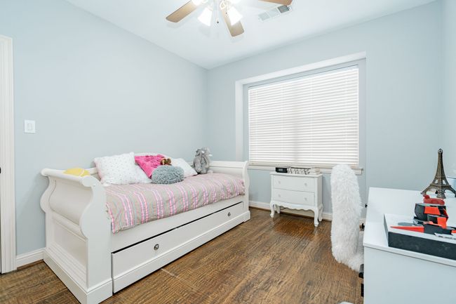 Bedroom featuring ceiling fan, baseboards, dark wood-style flooring, and visible vents | Image 24
