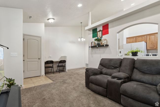 Living area with light colored carpet, a chandelier, light tile patterned floors, arched walkways, and recessed lighting | Image 10