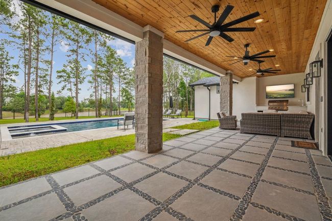 A beautifully crafted wooden-covered ceiling, complete with fans and ambient lighting, shelters a fully equipped outdoor kitchen—perfect for hosting unforgettable gatherings with family and friends. | Image 46