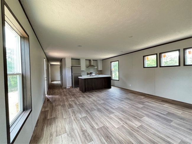 Countertops, open floor plan, wood look finished floors, and fridge | Image 12
