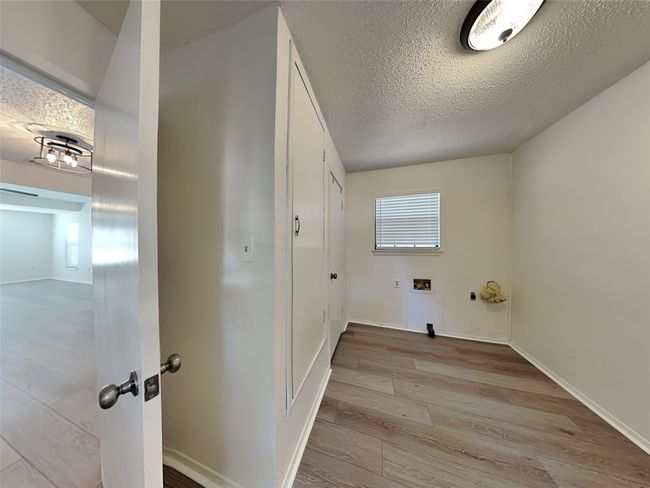 Laundry area with a textured ceiling, light wood-style floors, hookup for a washing machine, and baseboards | Image 14
