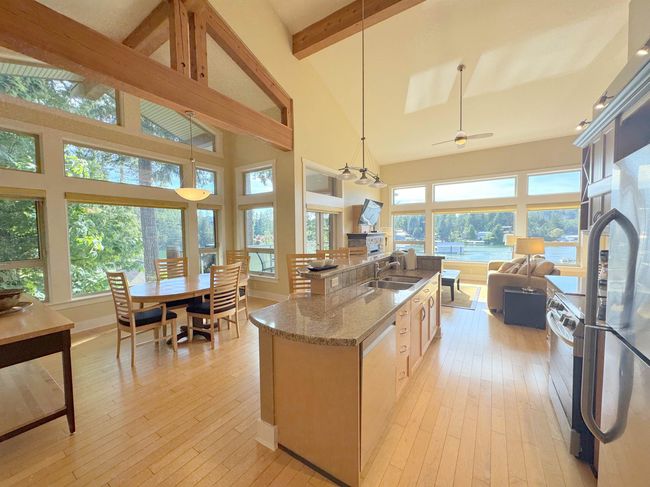 Kitchen featuring stainless steel appliances, beam ceiling, light stone countertops, light wood-style flooring, and open floor plan | Image 4