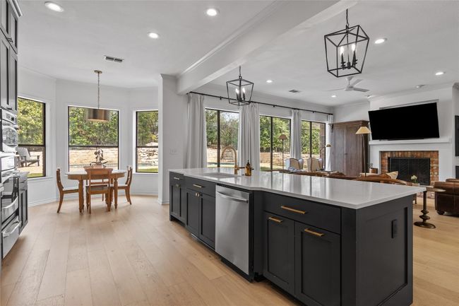 Kitchen with dishwasher, visible vents, ornamental molding, a sink, and a brick fireplace | Image 15