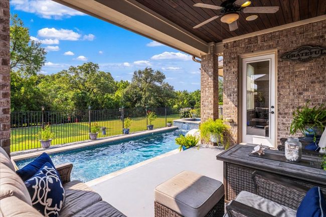 View of swimming pool featuring a fenced backyard, ceiling fan, a pool with connected hot tub, and a patio | Image 29