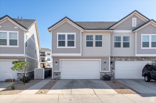 View of front of home with stone siding, an attached garage, and driveway | Image 30