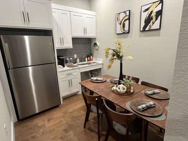 Kitchen featuring freestanding refrigerator, backsplash, white cabinetry, light countertops, and wood finished floors | Image 15