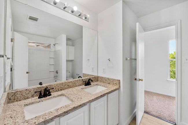 Full bathroom with double vanity, toilet, and shower / washtub combination | Image 30