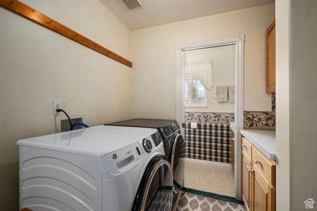Clothes washing area with washer and dryer, cabinet space, and visible vents | Image 29