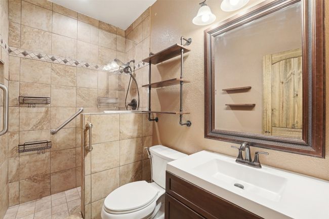 Bathroom featuring a textured wall, vanity, a shower stall, and toilet | Image 13