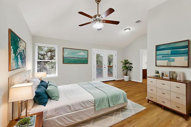 Bedroom featuring lofted ceiling, access to outside, multiple windows, light wood finished floors, and a ceiling fan | Image 5