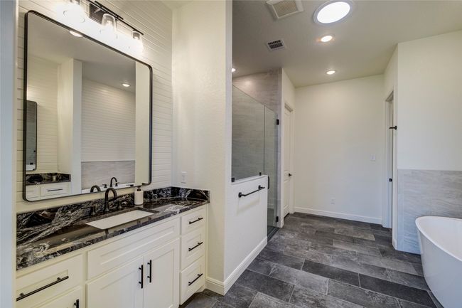 Bathroom featuring tile flooring, vanity with extensive cabinet space, and a bathing tub | Image 14