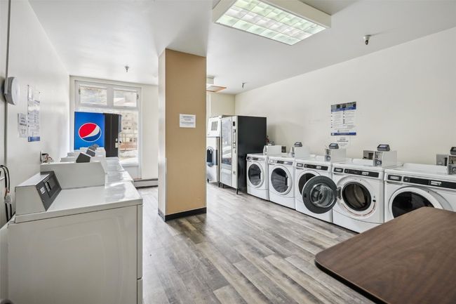 Community laundry room featuring baseboard heating, washer and clothes dryer, and wood finished floors | Image 37