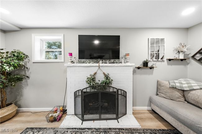 Living room with baseboards, wood finished floors, and a fireplace | Image 8