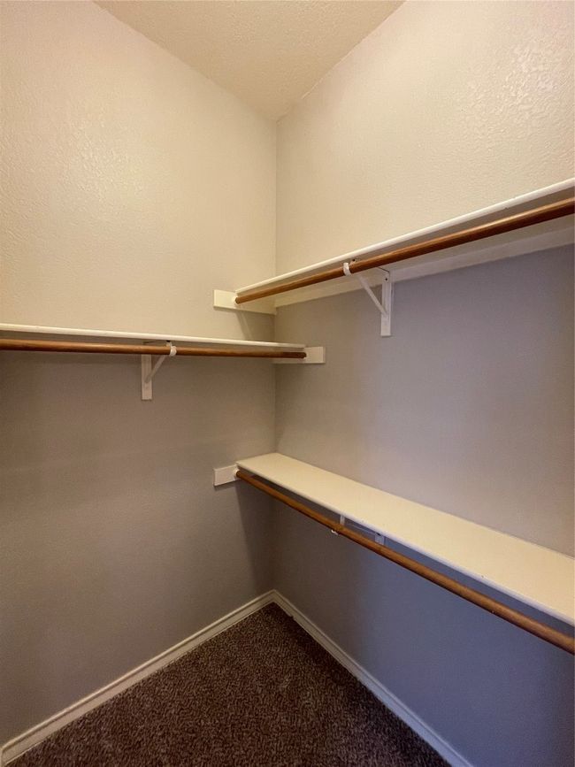 Walk in closet featuring dark colored carpet | Image 30