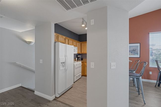 Kitchen featuring visible vents, light wood-type flooring, light countertops, baseboards, and white appliances | Image 5