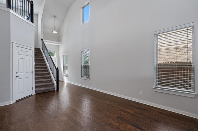 Unfurnished living room featuring stairway, wood finished floors, and high vaulted ceiling | Image 13