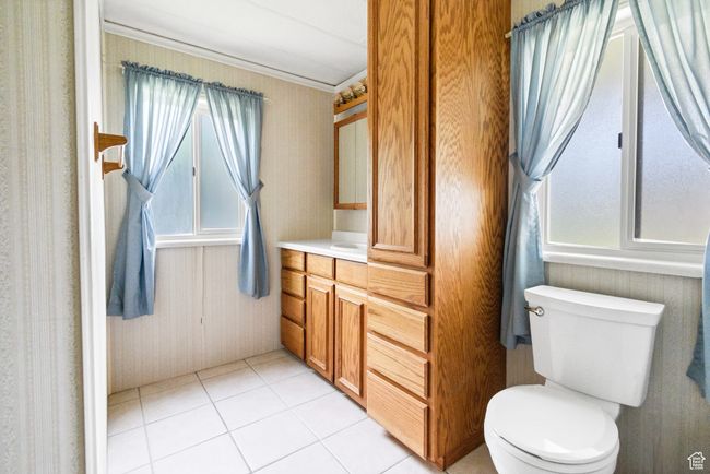 Half bathroom featuring healthy amount of natural light, vanity, toilet, tile patterned floors, and wallpapered walls | Image 17