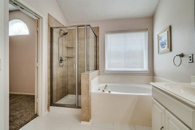 Bathroom featuring a textured ceiling, vanity, a shower stall, a bath, and light tile patterned flooring | Image 23
