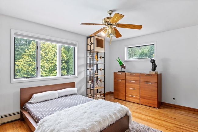 Bedroom with light wood finished floors, a baseboard radiator, baseboards, and ceiling fan | Image 24