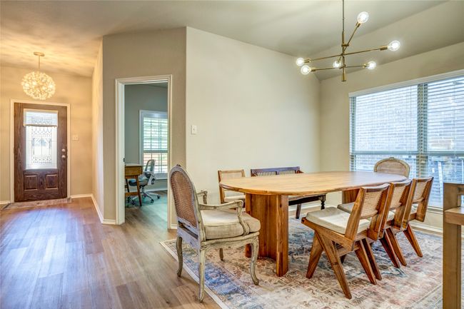 Dining room with light wood finished floors, a notable chandelier, baseboards, and vaulted ceiling | Image 9