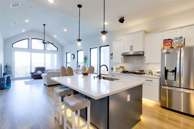 Kitchen with a sink, appliances with stainless steel finishes, under cabinet range hood, a center island with sink, and backsplash | Image 26