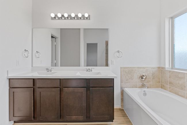Full bath featuring wood finished floors, double vanity, a sink, and a bath | Image 14
