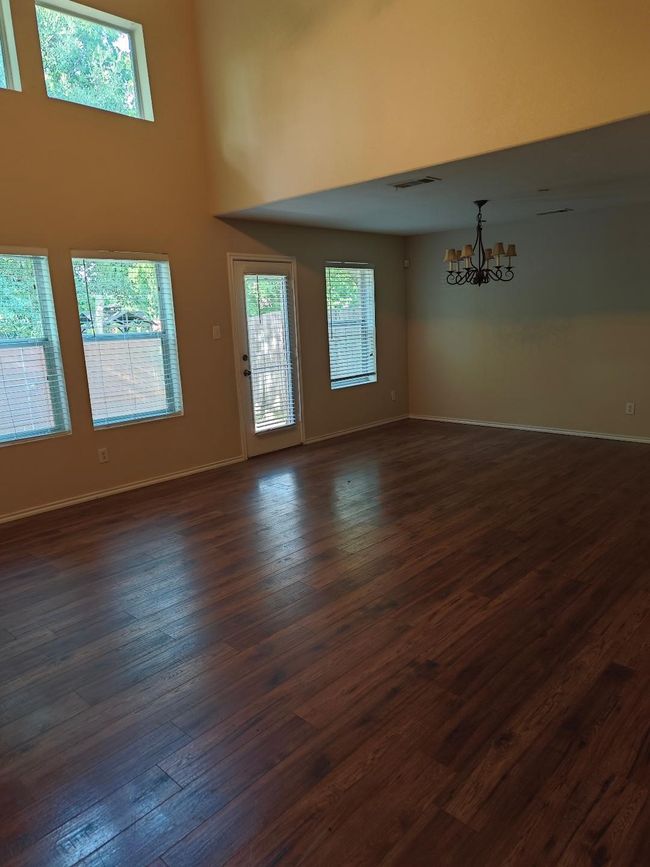 Spare room featuring a chandelier, dark wood-style floors, healthy amount of natural light, baseboards, and a high ceiling | Image 7