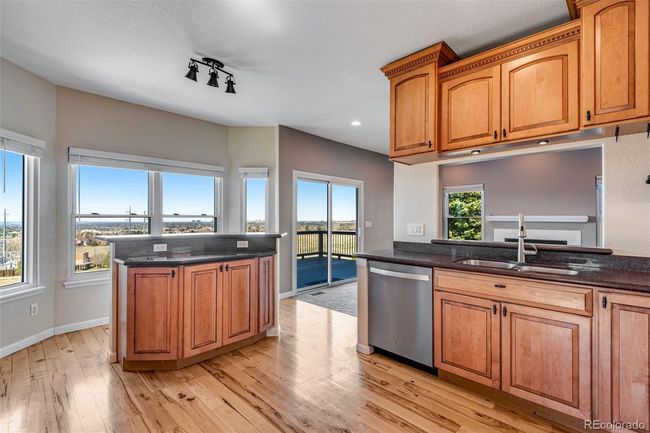 Kitchen with baseboards, light wood-style flooring, a kitchen island, stainless steel dishwasher, and a sink | Image 13